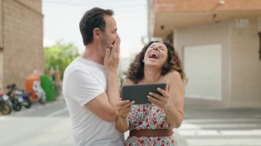 Man and woman couple smiling confident watching video on touchpad at street