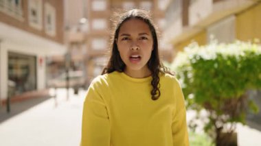 Young african american woman smiling confident doing hug gesture at street