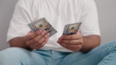 Young hispanic man counting dollars at home
