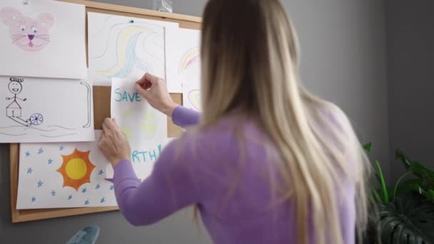 Junge Blonde Kindergärtnerin Hängt Kindergarten Korkbrett — Stockvideo
