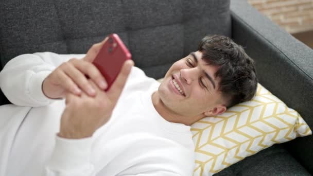 Junger Hispanischer Mann Mit Smartphone Hause Auf Sofa Liegend — Stockvideo