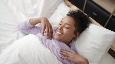 Afrikalı Amerikalı bir kadın yatak odasında kollarını açarak uyanıyor.