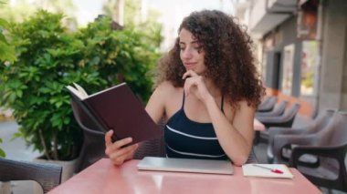 Kahve dükkanının terasında akıllı telefon kullanan genç ve güzel bir İspanyol kadın.