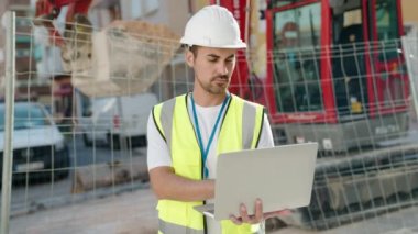 Young hispanic man architect using laptop at street