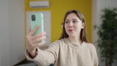 Young blonde woman having video call standing at home