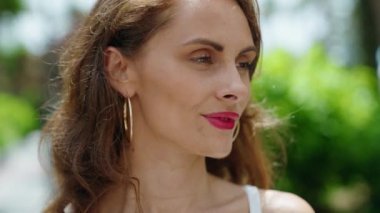 Genç, güzel, İspanyol bir kadın, gülümsüyor. Parkta kendine güveniyor.