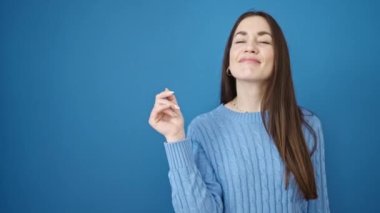Kafkasyalı genç bir kadın gülümsüyor, mavi arka plan üzerinde yan tarafı işaret ediyor.