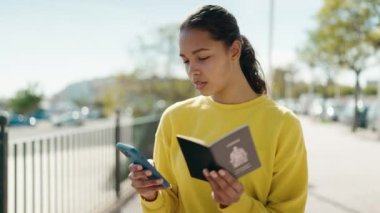 Amerika Birleşik Devletleri pasaportlu genç Afro-Amerikalı bir kadın sokakta akıllı telefon kullanıyor.
