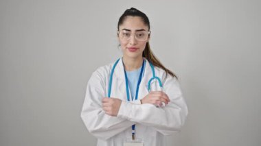 Genç, güzel İspanyol kadın doktor, gülümsüyor. Kollarını kavuşturup, izole beyaz arka planda hareketler yapıyor.