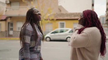 Two african american women smiling confident speaking at street