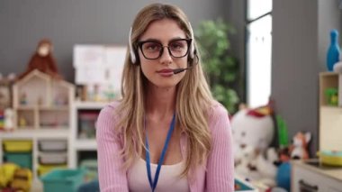 Young blonde woman teacher smiling confident having video call at kindergarten
