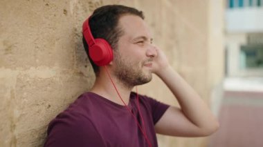 Genç adam kendinden emin bir şekilde, izole tuğla arka planda müzik dinliyor.