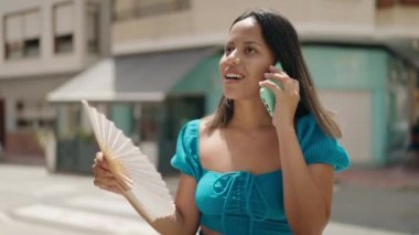 Genç İspanyol kadın akıllı telefondan konuşuyor. Sokakta pervane kullanıyor.