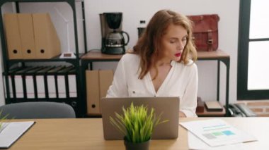 Young beautiful hispanic woman business worker using laptop reading document at office