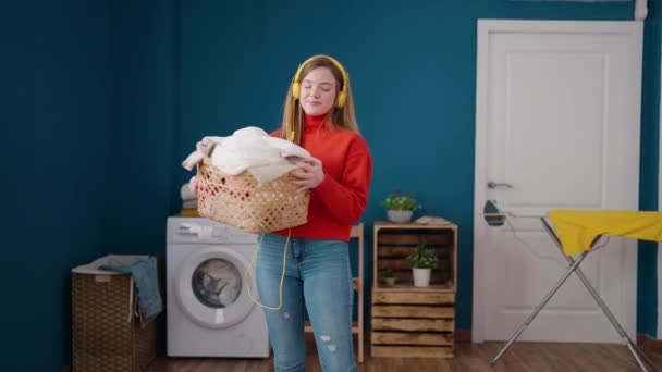 Ung Blond Kvinna Lyssnar Musik Kasta Kläder Korg Tvättstuga — Stockvideo