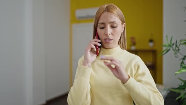Evde Ciddi Bir Ifadeyle Akıllı Telefondan Konuşan Genç Sarışın Kadın — Stok video