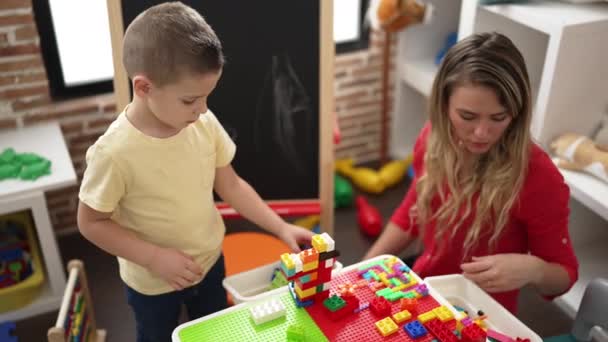 Teacher Toddler Playing Construction Blocks Sitting Table Kindergarten — Vídeo de stock