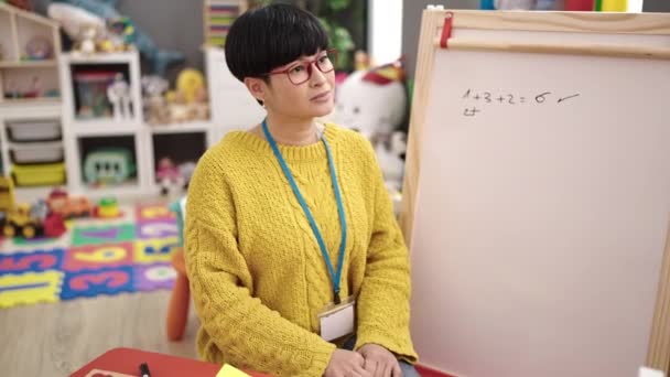 Młoda Chinka Nauczyciel Przedszkola Uśmiechnięta Pewnie Siedzi Krześle Przedszkolu — Wideo stockowe