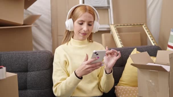 Młoda Blondynka Słuchająca Muzyki Siedzącej Kanapie Nowym Domu — Wideo stockowe