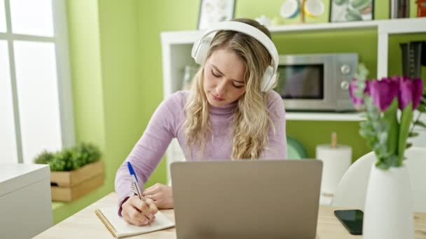 Młoda Blondynka Używa Laptopa Słuchawek Pisania Notatek Jadalni — Wideo stockowe