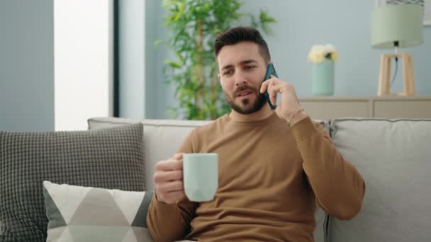 Mladý Hispánec Pije Kávu Mluví Doma Smartphonu — Stock video