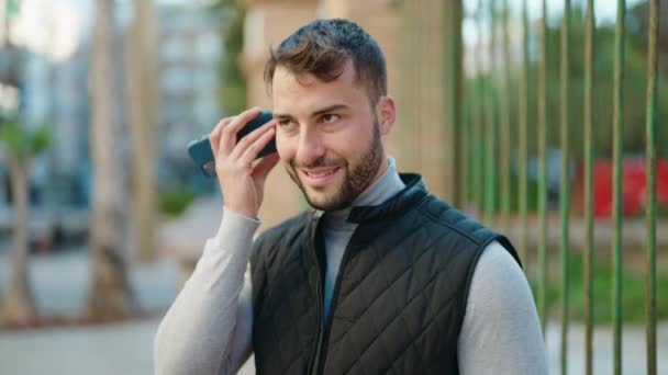 Молодий Іспаномовний Чоловік Посміхається Впевнено Слухаючи Аудіоповідомлення Смартфону Вулиці — стокове відео