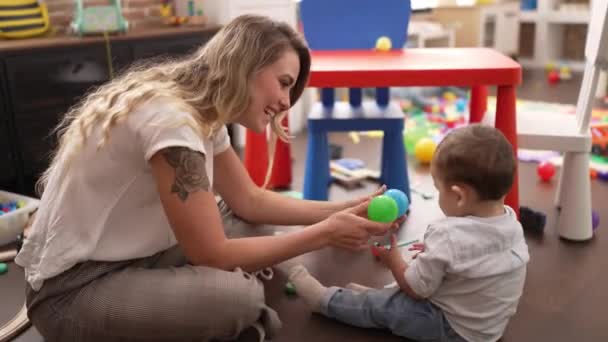 幼稚園の床に座っているボールで遊ぶ母親と息子 — ストック動画