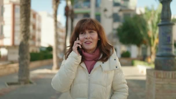Mujer Pelirroja Mediana Edad Sonriendo Confiada Hablando Teléfono Inteligente Calle — Vídeos de Stock