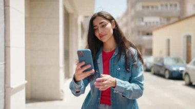 Genç İspanyol kız gülümsüyor. Kendine güveni tam. Sokakta akıllı telefonun yanında özçekim yapıyor.