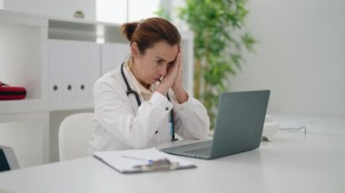 Klinikte doktor üniforması giyen orta yaşlı bir kadın.