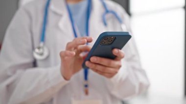 Klinikte akıllı telefon kullanan genç, güzel İspanyol kadın doktor.