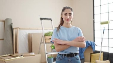 Young beautiful hispanic woman smiling confident standing with arms crossed gesture at new home