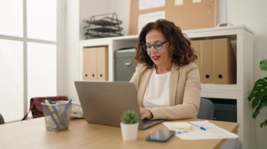 Middle age woman business worker using laptop working at office
