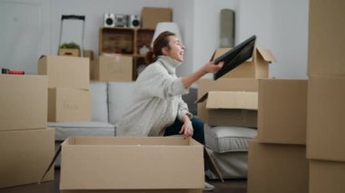 Middle age woman smiling confident unboxing package at new home