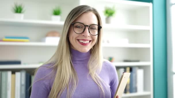 Jovem Loira Estudante Sorrindo Confiante Segurando Prancheta Universidade Biblioteca — Vídeo de Stock