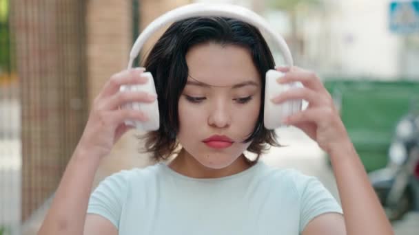 若いですヒスパニック系の女性は路上で音楽を聞いて — ストック動画