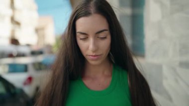 Young beautiful hispanic woman looking to the side with serious expression at street