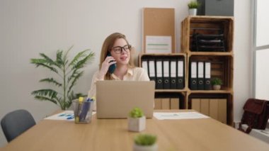Young blonde woman business worker talking on the smartphone working at office