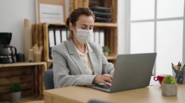 Middle age woman business worker wearing medical mask working at office