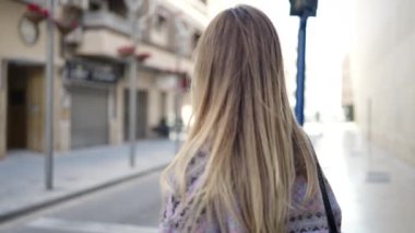 Sokakta kollarını kavuşturmuş genç sarışın kadın.