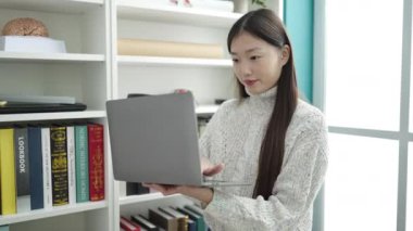 Young chinese woman student using laptop studying at library university