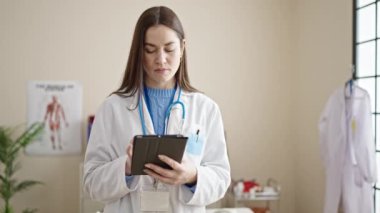 Genç beyaz kadın doktor klinikte dokunmatik ped kullanıyor.