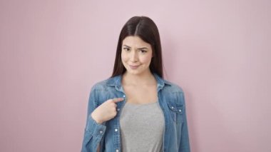 Genç, güzel İspanyol bir kadın, kendine güvenerek gülümsüyor ve pembe arka planda parmağıyla hayır diyor.