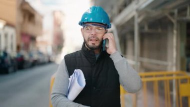 Young latin man worker with serious expression talking on the smartphone at street