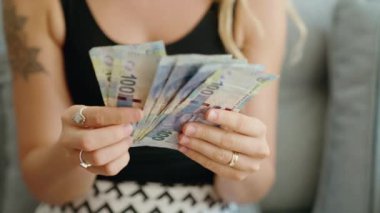 Genç bir kadın Güney Afrika 'da 100 rand banknot sayıyor.