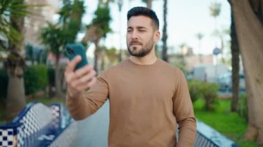 Parkta akıllı telefon kullanarak gülümseyen İspanyol genç adam.