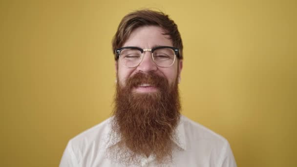 Młody Rudowłosy Człowiek Uśmiecha Pewny Siebie Nosząc Okulary Odizolowanym Żółtym — Wideo stockowe