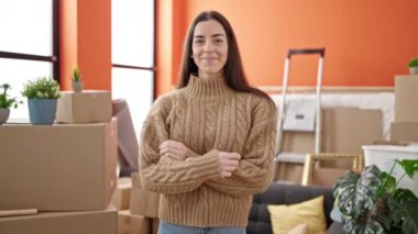 Young beautiful hispanic woman smiling confident standing with arms crossed gesture at new home
