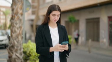 Genç İspanyol kız gülümsüyor. Kendine güveni tam. Sokakta akıllı telefonun yanında özçekim yapıyor.
