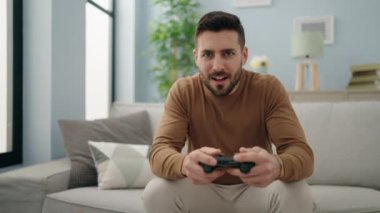 Evdeki kanepede oturan İspanyol asıllı genç oyun oynuyor.